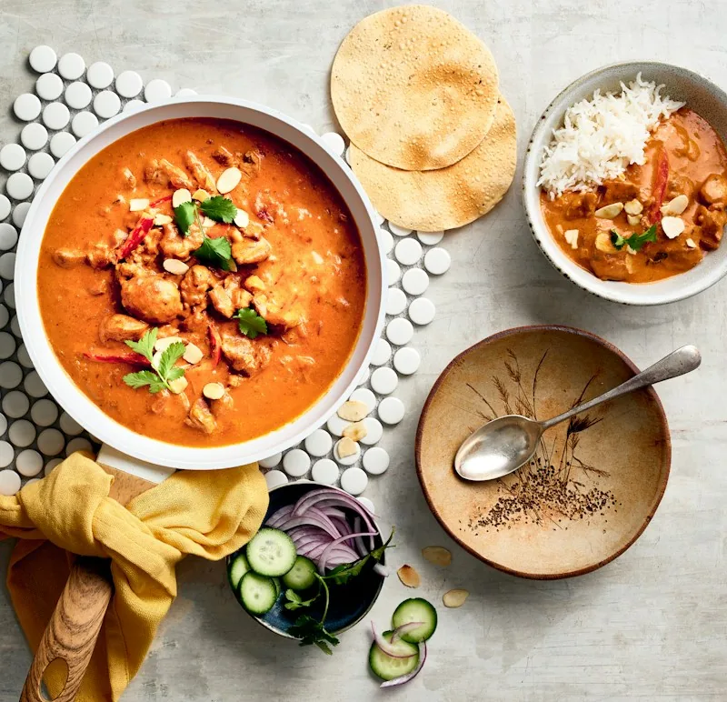 Bowl of chicken curry served with rice and papad