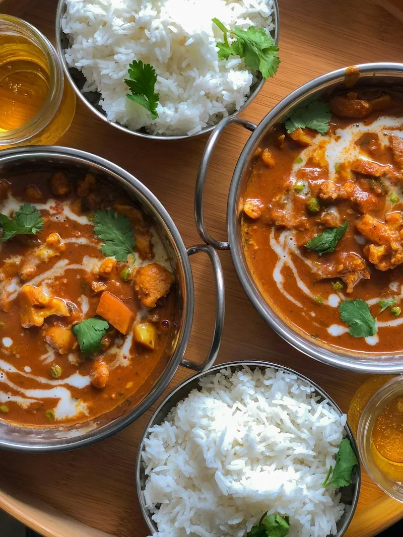 Creamy curries in steel bowls served with rice