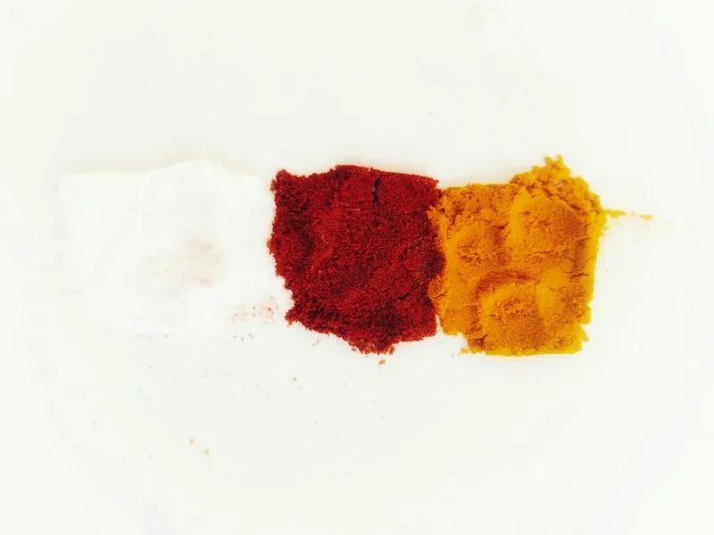 Ground red and yellow spice powders on a white surface